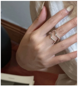 Detail of minimalist S925 silver double-layer wave ring worn on finger in warm lighting