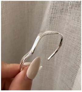 Macro detail of wave-shaped S925 sterling silver cuff with a high-polished mirror finish