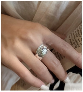 Detail of silver wide-band ring with irregular texture and artistic letter engraving
