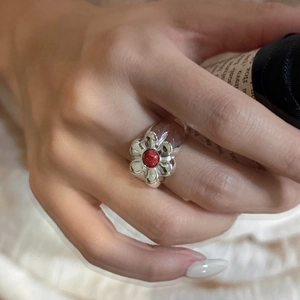Elegant S925 silver flower ring featuring a round red gemstone on model's hand