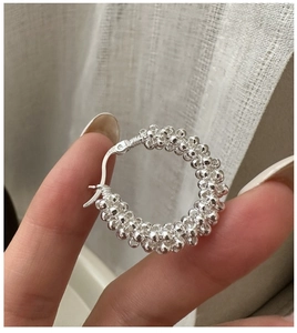 Détail de boucles d'oreilles créoles en argent 925 avec design texturé en perles