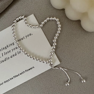 Polished S925 sterling silver beaded bracelet with adjustable slide clasp on elegant background