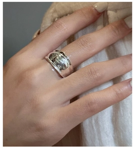 Macro shot of silver wide-band ring with letter engraving on textured background