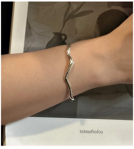 Detail shot of a minimalist S925 sterling silver wavy cuff bracelet on a female wrist