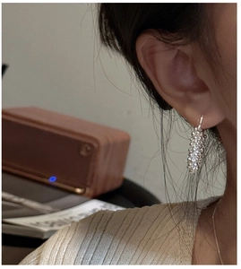 Gros plan de boucles d'oreilles pendantes en argent 925 sur un modèle sous lumière douce