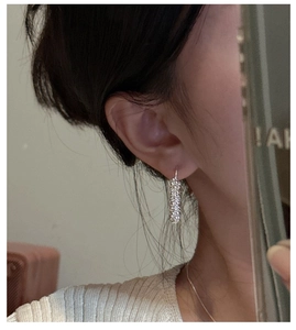 Détail de boucles d'oreilles torsadées en argent serties de cristaux scintillants