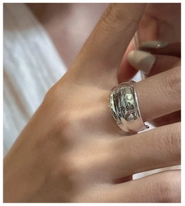 Close-up of wide S925 sterling silver band ring with engraved letters on finger