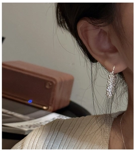 Détail de boucles d'oreilles créoles perlées argentées portées par un mannequin en intérieur