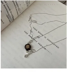 Detail of S925 silver necklace with brown bead pendant on an open vintage book background