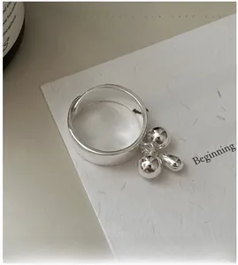 Close-up of S925 sterling silver ring with three hanging spheres on textured background
