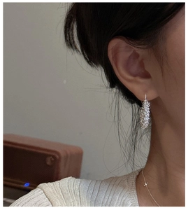 Gros plan de boucles d'oreilles créoles en argent 925 avec texture sur l'oreille