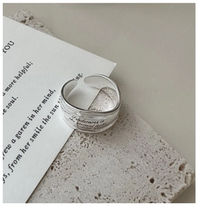 Macro detail of silver adjustable ring engraved with Tenderness is the eternal light