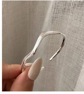 Detailed view of silver wavy open bangle with polished irregular minimalist design
