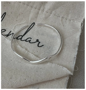 Macro detail of silver minimalist wavy bangle showing polished finish and sleek curves