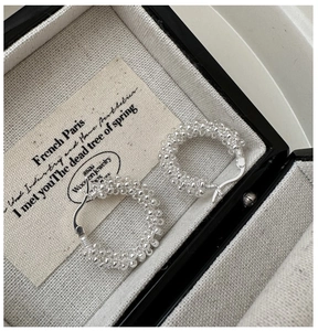 Détail de créoles en argent 925 avec texture perlée torsadée et fermoir à crochet classique