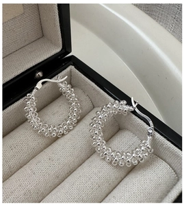 Vue macro de boucles d'oreilles créoles en argent 925 avec texture tressée dans un écrin