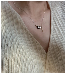 Detail of S925 silver necklace with black bead and asymmetric teardrop pendant on model