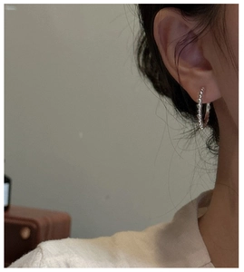 Gros plan d'une boucle d'oreille anneau perlée en argent 925 portée par un modèle