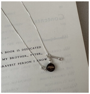 Detailed view of S925 silver necklace with black bead pendant on a book page