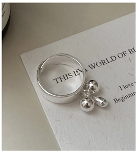Detailed macro view of an S925 sterling silver wide ring with a triple bead pendant charm