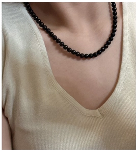 Detail of S925 sterling silver black glass beaded necklace worn on a V-neck sweater