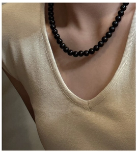 Close-up of elegant polished black crystal beaded necklace worn on a V-neck sweater