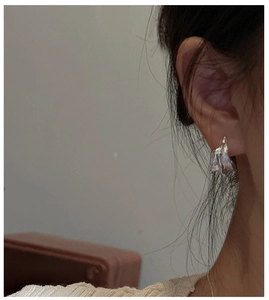 Side view of a model wearing silver S925 sterling silver earrings with wavy texture