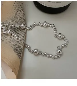 Detailed close-up of 925 sterling silver beaded necklace on vintage newspaper background