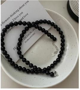 Detail of black beaded necklace with silver heart pendant on a white ceramic tray
