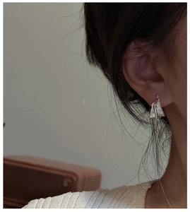Close-up of S925 sterling silver earrings with irregular textured curved wing design