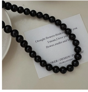 Macro detail of glossy black S925 silver beaded necklace on an elegant art card background