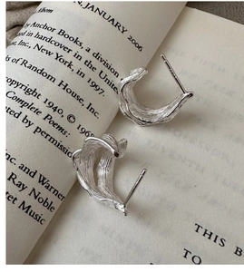 Macro shot of S925 sterling silver hoop earrings with lava texture on vintage book paper