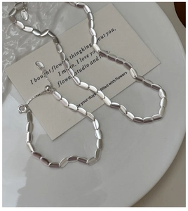 Detail of matte silver beaded necklace with adjustable sliding buckle on white ceramic