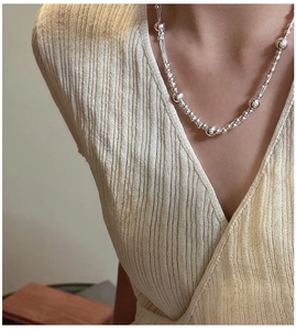 Detailed close-up of 925 sterling silver beaded layered necklace on female neck