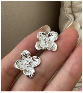 Macro shot of silver flower earrings showing intricate petal texture and metallic finish