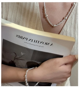 Macro shot of layered S925 sterling silver bead necklace and bracelet on a model