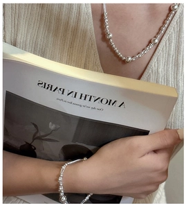 Detailed view of 925 sterling silver beaded layered necklace on a model holding a book