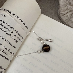 Retro S925 sterling silver water drop necklace on book page with brown pendant