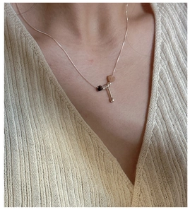 Detail of S925 silver necklace featuring a heart stone and bead on a ribbed knit top