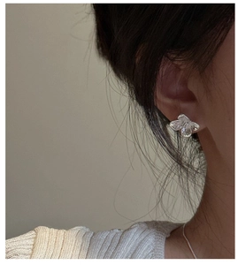 Close-up of S925 sterling silver floral stud earring worn by a model in soft lighting