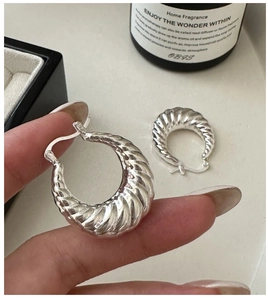Vue macro de boucles d'oreilles croissant en argent S925 avec texture ondulée élégante