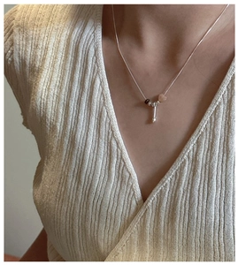 Close-up of S925 silver necklace with heart, bead, and bar pendants worn on a V-neck shirt