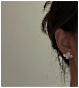 Detailed close-up of a delicate silver butterfly stud earring worn on the earlobe