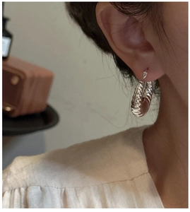 Vue rapprochée d'une boucle d'oreille créole croissant en argent S925 à texture torsadée