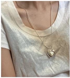 Gros plan détaillé d'un pendentif coeur 3D sur un collier de perles pour femmes