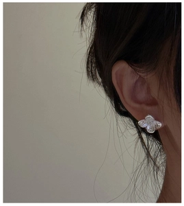 Close-up of a silver irregular flower stud earring with textured metal on female model