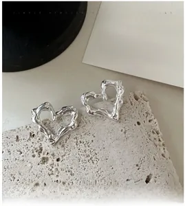 Dettaglio macro di orecchini a cuore in argento S925 con finitura in metallo liquido testurizzato