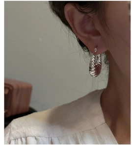 Gros plan de créoles croissant en argent sterling S925 avec design à vagues texturées
