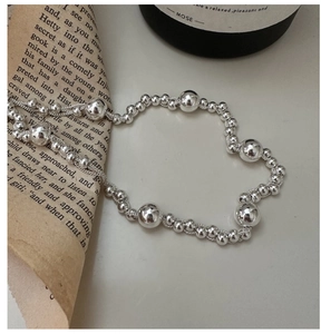 Detailed view of polished S925 sterling silver beaded necklace over vintage paper