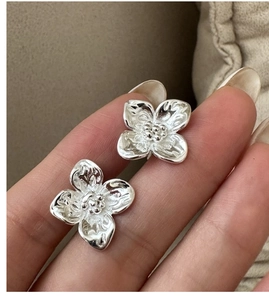Detailed view of silver flower stud earrings with hammered texture and floral design